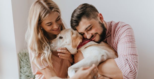 homem e mulher abrançando cão labrador