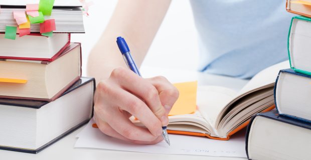 Student reading a book and writing the notes