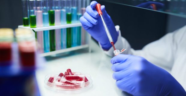 Close up of unrecognizable scientist dropping blood samples in test tubes while working on research in laboratory, copy space